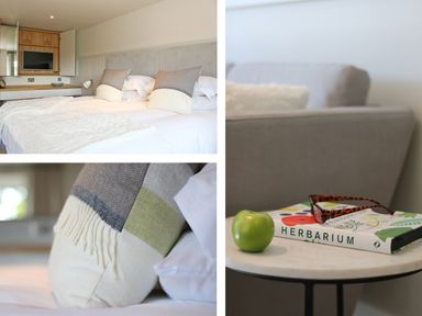 A bedroom with a bed with pillows and a throw blanket a close up of a pillow and a side table with a book apple and glasses at Mill House Boskensoe Barns Mawnan Smith near Falmouth