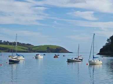Several boats anchored on calm water with green hills and trees in the background at Mill House Boskensoe Barns Mawnan Smith near Falmouth