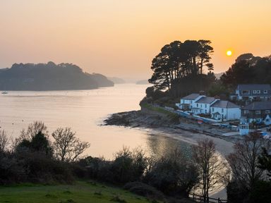 A coastal scene with houses near a beach and trees at sunset at Mill House Boskensoe Barns Mawnan Smith near Falmouth