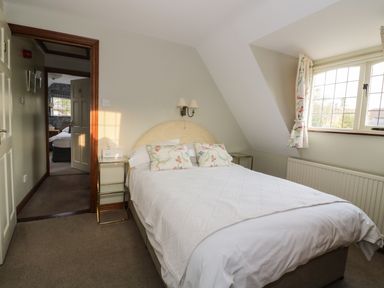 A bedroom with a bed and bedside tables near a window at The Lodge off High Street in Hadleigh