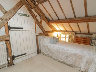 A bedroom with a single bed a wooden door and a dresser with drawers at Lower Dolgenau- The Cottage in Llawryglyn near Llanidloes