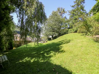 A grassy garden area with trees and outdoor chairs at Lower Dolgenau- The Cottage in Llawryglyn near Llanidloes