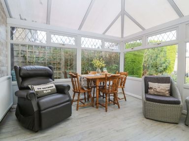 A conservatory with a dining table and chairs at The Cottage in Marian-Glas