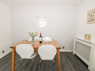 A dining room with a wooden table set with wine glasses flowers and a bottle of wine at 11 Camden Building in Kendal