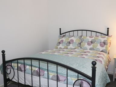 A bedroom with a metal framed double bed with patterned bedding and a nightstand at 11 Camden Building in Kendal