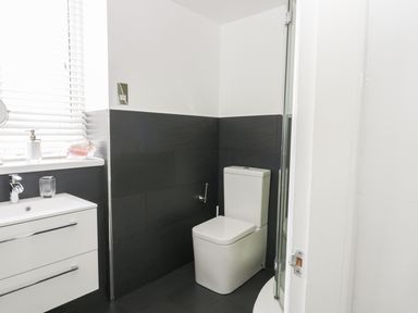 A bathroom with a toilet and a sink with drawers next to a window with blinds at 11 Camden Building in Kendal