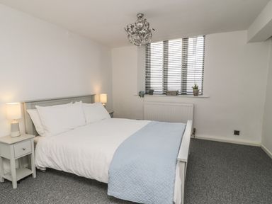 A bedroom with a double bed side tables lamps and a window with blinds at 11 Camden Building in Kendal