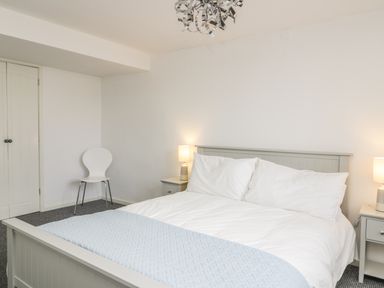A bedroom with a bed and side tables with lamps and a chair in the corner at 11 Camden Building in Kendal