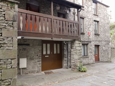 A stone building with a wooden balcony and brown doors at 11 Camden Building in Kendal