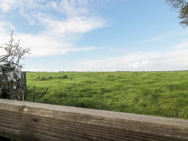 A green field with grass under a blue sky with clouds at Poppy Cottage in Llantwit Major