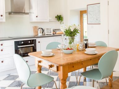 A kitchen with a wooden table set with bowls cups and a vase of flowers at Salters Black Dog near Crediton