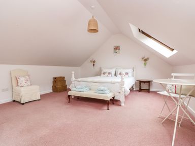 A bedroom with a white bed bench and table with chairs under a skylight at Bolitho's Retreat in Helford