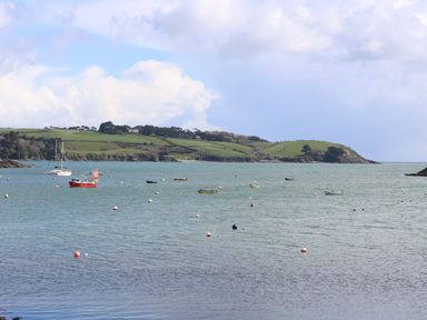 A coastal view with boats and buoys on the water and green hills in the background at Bolitho's Retreat in Helford