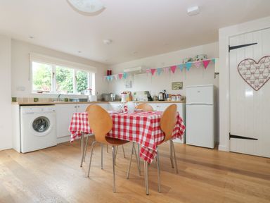 A kitchen with a table covered with a red and white checkered tablecloth and four chairs at Bolitho's Retreat in Helford