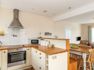 A kitchen with wooden countertops white cabinets and a dining table with chairs at Bolenowe in Trebetherick near Polzeath