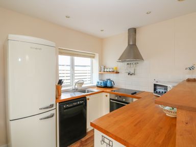 A kitchen with wooden countertops a white refrigerator a black dishwasher a window a stainless steel oven a blue kettle and toaster at Bolenowe Trebetherick near Polzeath