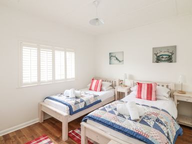 A bedroom with two single beds each with a quilt and red striped pillow at Bolenowe Trebetherick near Polzeath
