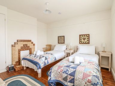 A bedroom with two single beds with patchwork quilts and towels on them at Bolenowe in Trebetherick near Polzeath