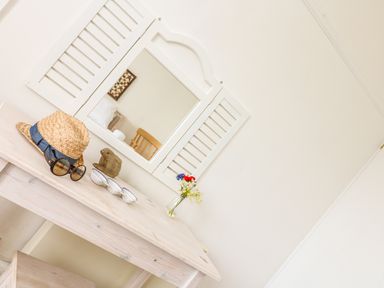 A wooden table with a straw hat sunglasses ceramic rabbit three small bowls and a vase with flowers in front of a white wall mirror at Bolenowe Trebetherick near Polzeath