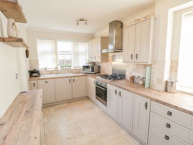 A kitchen with wooden countertops cabinets a gas stove and a sink under the window at Lilly May Cottage in Flamborough