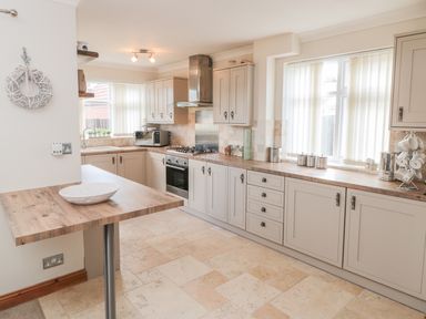 A kitchen with wooden countertops cabinets a stove microwave and windows with blinds at Lilly May Cottage in Flamborough