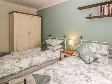 A bedroom with two single beds bedside table with lamp and wardrobe at Lilly May Cottage in Flamborough