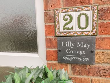 A close up of house number 20 and Lilly May Cottage nameplate on a brick wall