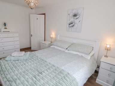 A bedroom with a double bed bedside tables lamps and a chest of drawers at Lilly May Cottage in Flamborough