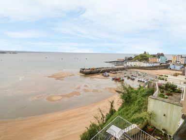 A view of a harbor with boats on the sand and a small town with colorful buildings by the sea at Apartment 2 in Tenby