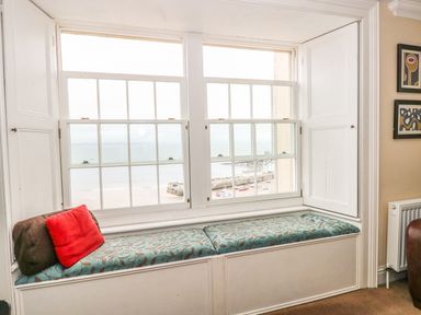 A window seat with cushions and pillows in a room with a view of the sea at Apartment 2 in Tenby