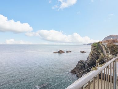 A coastal view with rocks in the sea and a stone staircase on a cliff at Oceans Side in Ilfracombe