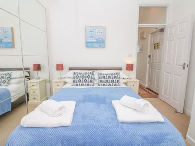 A bedroom with a bed covered with a blue blanket and two white towels at Oceans Side in Ilfracombe