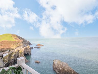 A coastal cliff with a road and rocks in the sea at Oceans Side in Ilfracombe