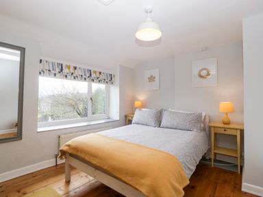 A bedroom with a double bed two bedside tables with lamps a window and a mirror at Pippins in Bream