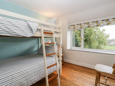 A bedroom with bunk beds near a window and a wooden chair at Pippins in Bream