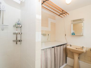 A bathroom with a shower, a sink with two taps, a mirror, and a drying rack at Pippins in Bream
