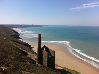 A coastal landscape with an old stone building and chimney near a sandy beach and ocean at Ash in Truro