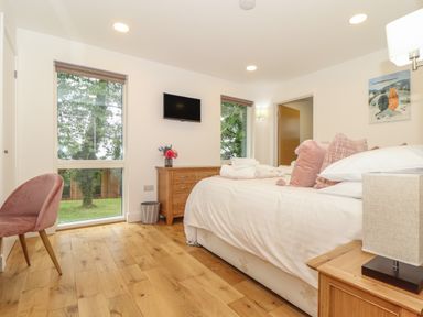 A bedroom with a bed pillows side tables a dresser a chair and two windows at Ash in Truro