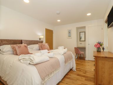 A bedroom with a large bed with pillows and towels beside a wooden dresser and a chair at Ash in Truro
