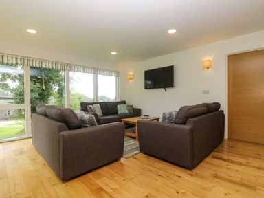 A living room with two sofas a wooden coffee table and a wall mounted television at Ash in Truro