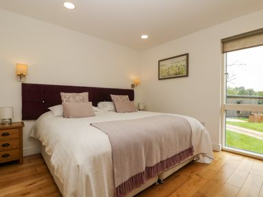 A bedroom with a double bed nightstands lamps and a large window at Ash in Truro