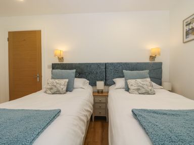 A bedroom with two single beds white bedding blue headboards and blue throws at Ash in Truro