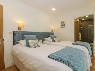 A bedroom with two single beds with blue headboards and blankets at Ash in Truro