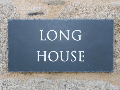 A sign reading long house on a stone wall at Long House Boskensoe Barns in Mawnan Smith