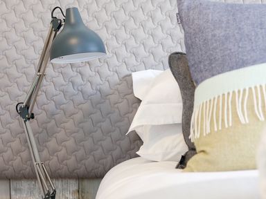 A bedside area with a gray adjustable lamp and pillows on a bed at Long House Boskensoe Barns in Mawnan Smith