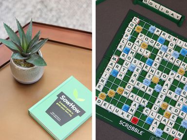 A potted plant and a green book titled Sow How on a table and a Scrabble game board with words on it at Long House Boskensoe Barns in Mawnan Smith