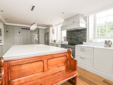 A kitchen with a wooden bench and white island counter at Capel Bryn Bachau in Chwilog near Criccieth
