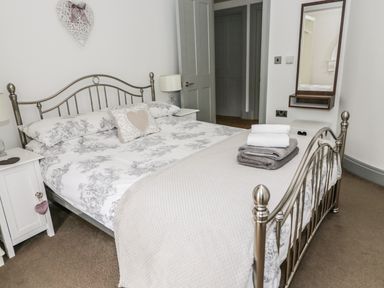 A bedroom with a metal bed frame white bedding with patterns bedside tables with lamps and a wall mirror at Capel Bryn Bachau Chwilog near Criccieth