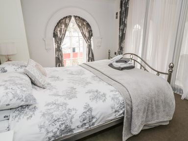 A bedroom with a double bed a window with curtains and folded towels on the bed at Capel Bryn Bachau in Chwilog near Criccieth