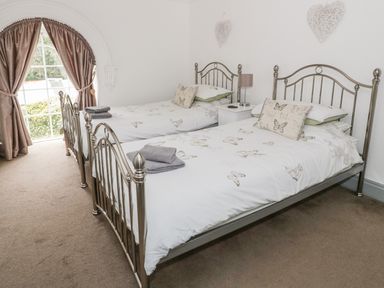 A bedroom with two single metal beds with butterfly bedding and beige curtains at Capel Bryn Bachau in Chwilog near Criccieth